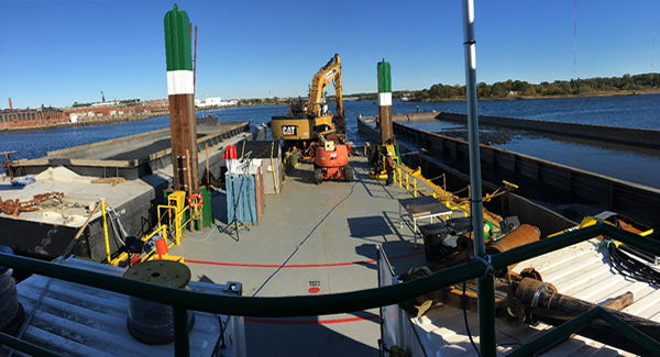 A precision mechanical dredging bucket filling a scow with contaminated sediment in the Lower Harbor during the fall of 2017 prior to dewatering and placement in the LHCC.