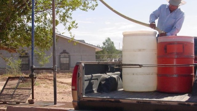 Man filling up water drums at water hauling station in Ganado