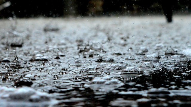 A closeup of a puddle with splashing due to rain falling.