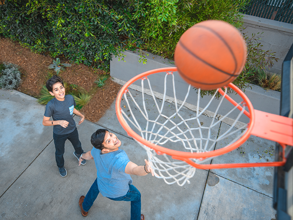 Kids playing basketball alongside a landscape.