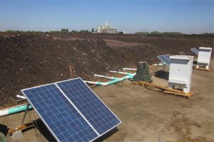 Solar panel and pvc tubing going into mounds of compost.