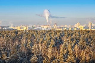 Stock photo showing a plume of steam rising from a smokestack in a city