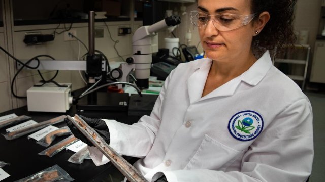 An EPA research engineer sitting in lab next to bench top with samples of lead service lines.