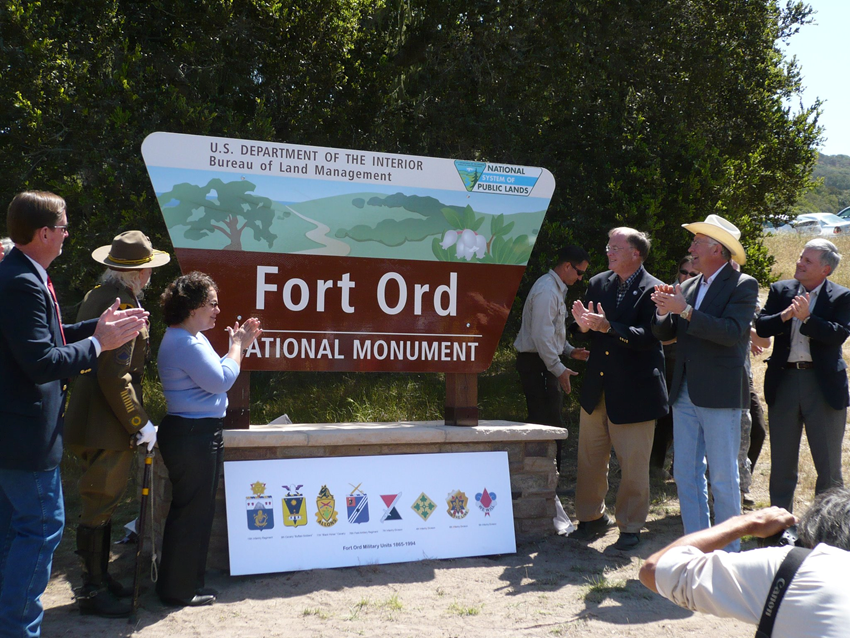 People clapping outside at a sign that reads 'US Department of the Interior, Bureau of Land Management, Fort Ord National Monument'