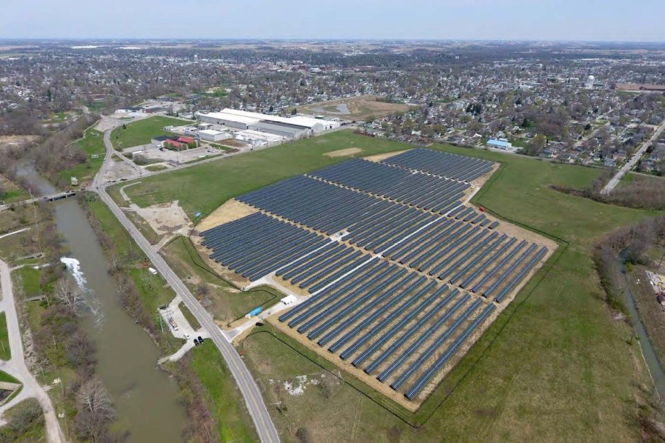 Photograph showing a large array of solar panels with Wildcat Creek on the left side and homes and buildings in the background.