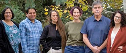 A group of six people posing for a photo outside