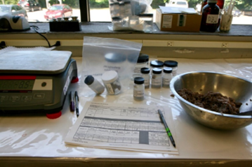 Laboratory table top with scale, labeled sample containers, sampling form, and stainless-steel bowl with fish paste.