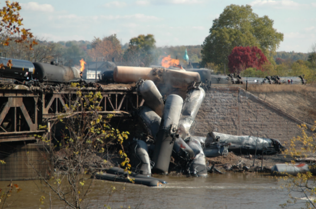 Train with multiple tank car derailment off a bridge into a river.