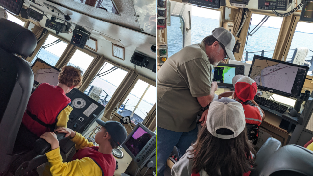 LEII captain supervises children as they sit in the captain's seat of the ship.