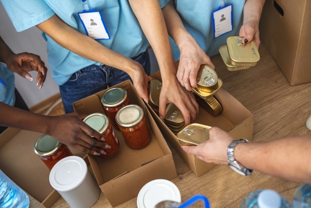 close up of volunteer-hands as they sort food donations as mason jars and canned food