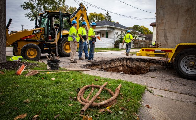 People working on pipes under the street