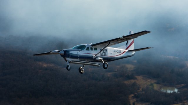 A white plane with ASPECT emblazoned on the side in flight.