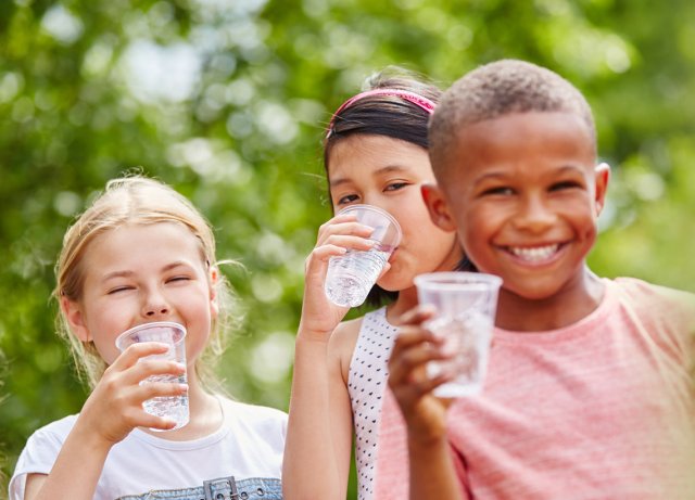 Children drinking from clear plastic cups of clear water