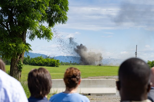 an open detonation of hazardous waste with a crowd watching from afar