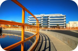 Wide-angle view of the Hyperion Water Reclamation Plant, including a view of outdoor wastewater treatment infrastructure and a six-story office building.