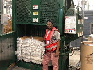 Photo of a man standing next to a trash compactor. 