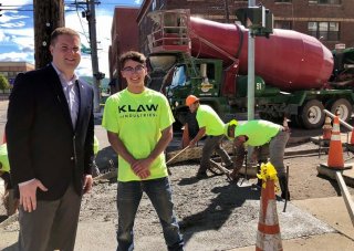 Two people standing side by side in front of red cement truck