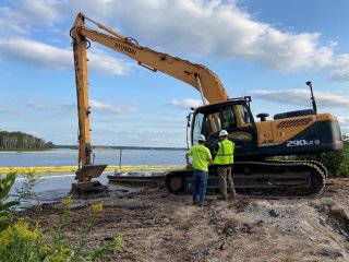 The first scoop of contaminated sediment is removed from Munger Landing.