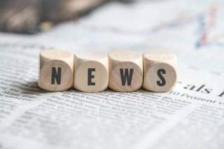 Four small wooden cubes next to each other spelling out news.