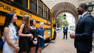 Four girls stand in front of a school bus as they are meeting Administrator Reagan at EPA HQ