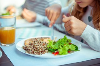 A child eating a healthy dinner with fish, salad and quinoa.