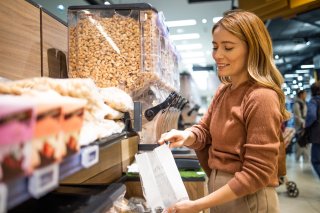 Woman refilling a bag of nuts from a large container