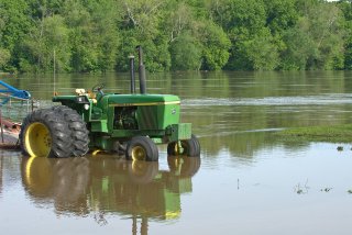 Green tractor in standing floodwater.