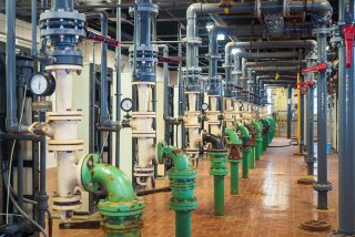 Water treatment facility with many grey and green pipes.