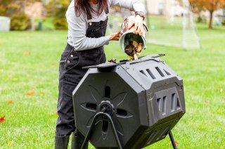 Woman pours food scraps from white bucket into black composting bin