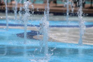 Splash pad water feature that sprays upward