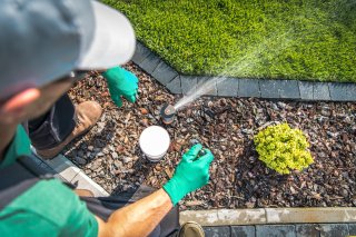 Image of a man working on a sprinkler head in a garden.