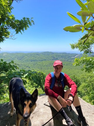 epa researcher emma d'ambro posing on a hike with her german shepherd dog smiling