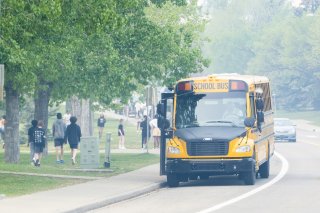 A School bus picking up students during a smoky and hazy day during wildfire smoke event.