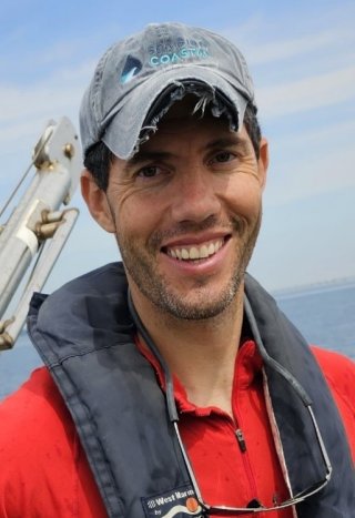 EPA researcher Brandon Jarvis smiling headshot wearing a hat on a boat out on the water